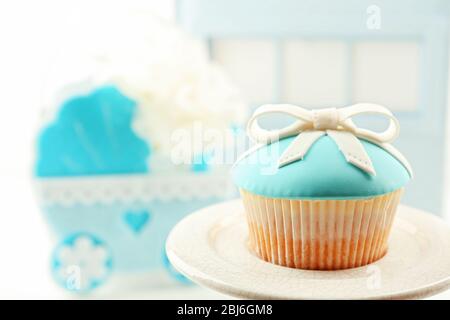 Petits gâteaux savoureux avec arc et les chaussons bébé, landau décoratif sur un fond de couleur Banque D'Images