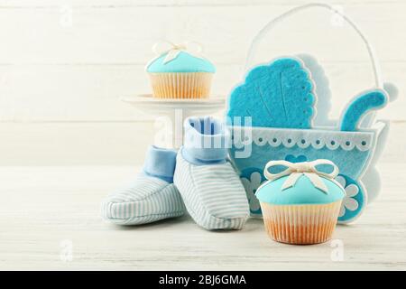 Petits gâteaux savoureux avec arc et les chaussons bébé, landau décoratif sur un fond de couleur Banque D'Images