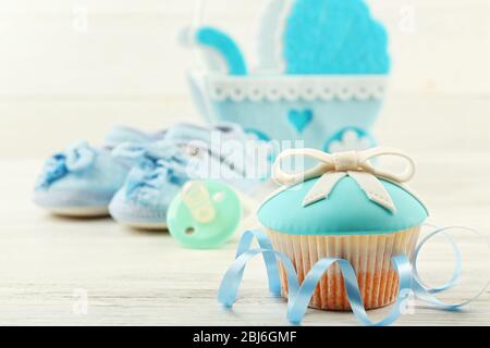 Petits gâteaux savoureux avec arc et les chaussons bébé, landau décoratif sur un fond de couleur Banque D'Images