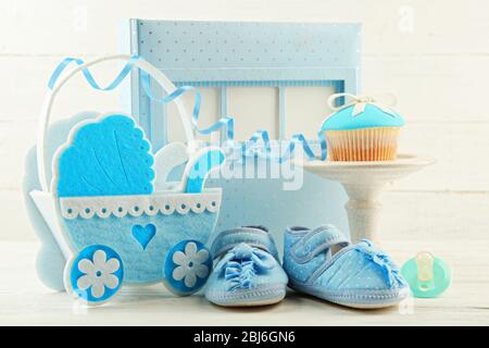 Délicieux cupcakes avec noeud et chaussures de bébé, chariot de bébé décoratif et album photo sur fond de couleur Banque D'Images