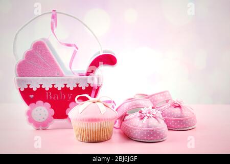 Petits gâteaux savoureux avec arc et les chaussons bébé, landau décoratif sur un fond de couleur Banque D'Images