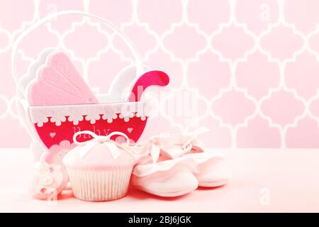 Petits gâteaux savoureux avec arc et les chaussons bébé, landau décoratif sur un fond de couleur Banque D'Images