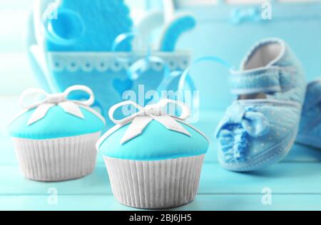 Délicieux cupcakes avec noeud et chaussures de bébé, chariot de bébé décoratif et album photo sur fond de couleur Banque D'Images