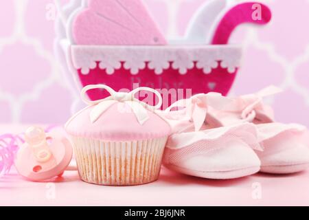 Petits gâteaux savoureux avec arc et les chaussons bébé, landau décoratif sur un fond de couleur Banque D'Images