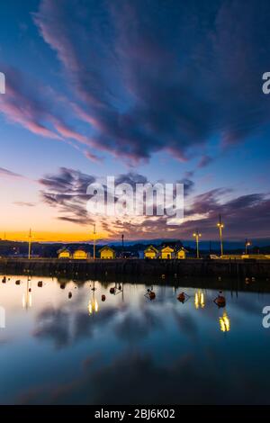 West Bay, Dorset, Royaume-Uni. 28 avril 2020. Météo britannique. Les nuages commencent à se dégager au-dessus du port peu après le coucher du soleil à la station balnéaire de West Bay à Dorset après une journée de pluie légère et de ciel couvert. Crédit photo : Graham Hunt/Alay Live News Banque D'Images