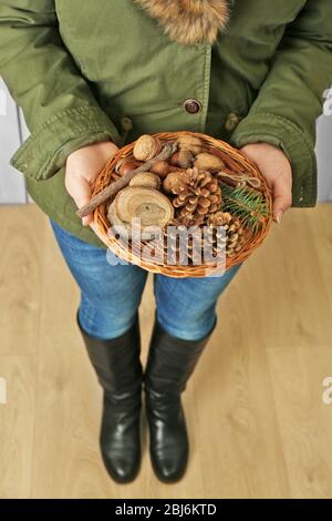 Femme au pelage tenant un panier en osier avec des noix et vert Banque D'Images