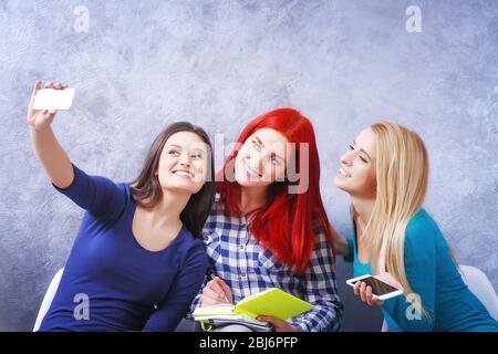 Les jeunes filles assis sur une chaise et prendre photo de leur propre chambre grise Banque D'Images