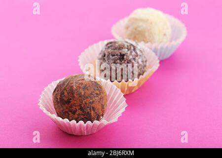 Trois truffes au chocolat dans des gobelets en papier, sur fond rose Banque D'Images