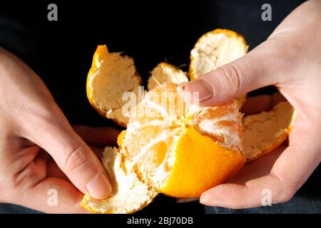 Femme peeling main mûre douce mandarine, gros plan Banque D'Images