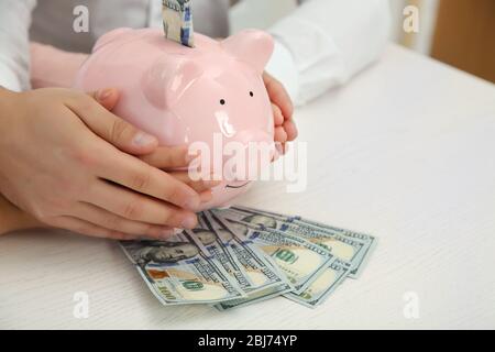 Un jeune couple heureux tenant dans la banque de piggy mains avec des billets en dollars. Concept d'économies d'argent Banque D'Images