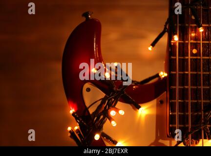 Guitare électrique avec guirlande éclairée sur fond de bois Banque D'Images