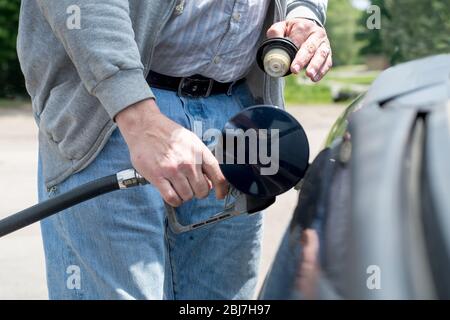 L'homme utilise une buse de gaz et un tuyau pour remplir son véhicule de carburant comme station-service aux États-Unis Banque D'Images