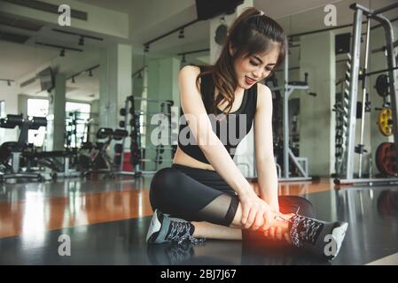Une femme asiatique se blessa pendant l'entraînement au genou dans le centre de fitness sportif. Concept médical et de santé. Thème de l'exercice et de la formation. Les gens en bonne santé l Banque D'Images