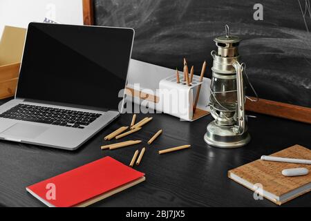 Bureau avec ordinateur portable et autres éléments sur fond de tableau noir Banque D'Images