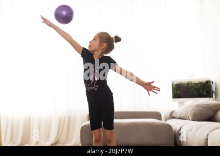 La fille fait de la gymnastique à la maison. Didacticiel vidéo de gymnastique. Exercices de gymnastique. L'idée d'une activité d'enfant en quarantaine Banque D'Images