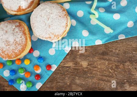 Délicieux beignets sucrés avec serviette bleue sur table en bois, vue sur le dessus Banque D'Images