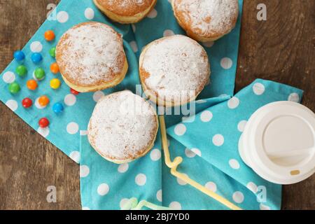 Délicieux beignets sucrés avec serviette bleue sur table en bois, vue sur le dessus Banque D'Images