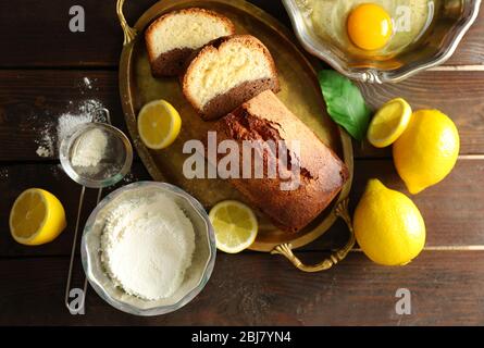 Délicieux pain sucré à gâteaux dans un plateau métallique avec citrons sur table en bois, vue sur le dessus Banque D'Images
