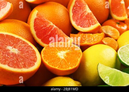 Agrumes mélangés colorés triés et alignés en rangées avec des tranches et des moitiés, gros plan Banque D'Images