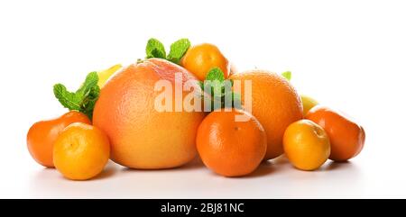 Un tas d'agrumes mélangés comprenant un pamplemousse, des oranges, des citrons, des clémentines, des mandarines avec des branches de menthe isolées sur un fond blanc, près de u Banque D'Images