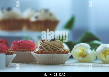 Délicieux cupcakes et tulipes blanches sur une table blanche, gros plan Banque D'Images