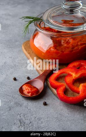 Ajvar dans un bocal en verre sur un fond gris. Gros plan Banque D'Images