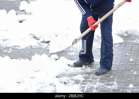 L'homme déneige à l'extérieur sur un chemin de voiture après le blizzard Banque D'Images