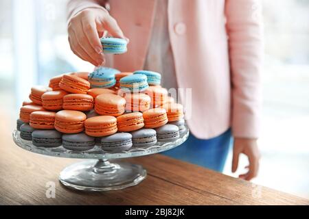 Main féminine prenant un délicieux macaron de plat sur la table Banque D'Images