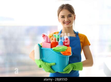 Concept de nettoyage. La jeune femme tient un bassin en plastique avec des liquides de lavage et des chiffons dans les mains Banque D'Images