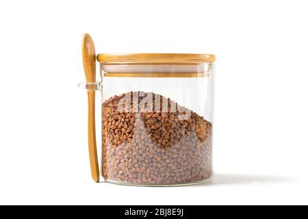 Grains de sarrasin brun dans un pot en verre avec cuillère en bois et couvercle sur fond blanc isolé nourriture saine, concept de supernourriture. Banque D'Images