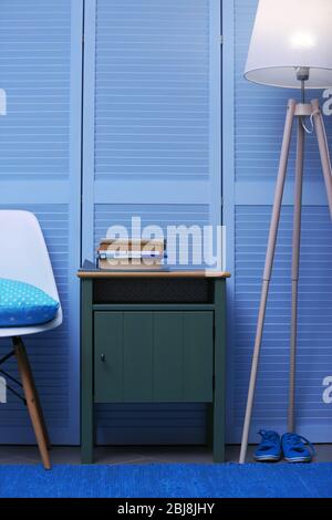 Petite table verte avec livres et lampe près de la garde-robe en bois bleu Banque D'Images