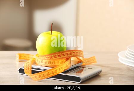 Pomme avec pèse-personne centimètre et balance de cuisine numérique sur table en bois Banque D'Images