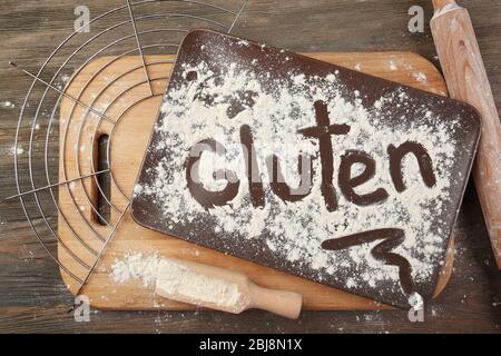 Mot gluten écrit avec de la farine sur un plateau au-dessus de la table en bois Banque D'Images