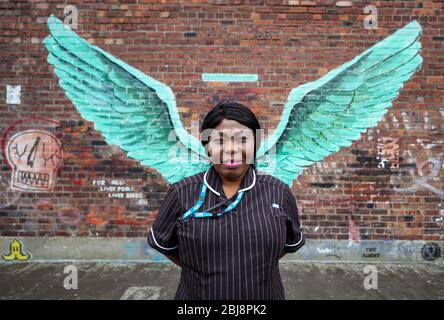 Susan Tay, une communauté de Matron à Mersey Care NHS, se tient devant les ailes d'oiseaux du foie, une œuvre de Paul Curtis sur un mur dans le Triangle balte de Liverpool. Banque D'Images