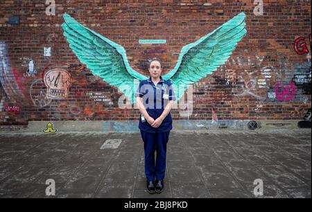 Erica Daly, chef d'équipe infirmière de district chez Mersey Care NHS, se tient devant les « ailes d'oiseaux du foie », une œuvre de Paul Curtis sur un mur du Triangle balte de Liverpool. Banque D'Images