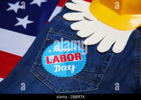 Concept de journée de travail. Casque, gants et jeans jaunes sur fond drapeau américain Banque D'Images