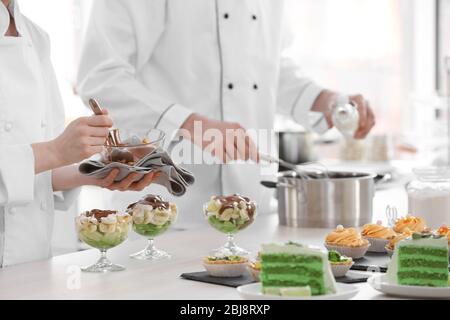 Chefs qui préparent et verse de la sauce au chocolat sur un dessert aux fruits. Banque D'Images