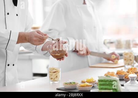 Chef mâle qui verse de la sauce au chocolat sur un dessert aux fruits. Banque D'Images