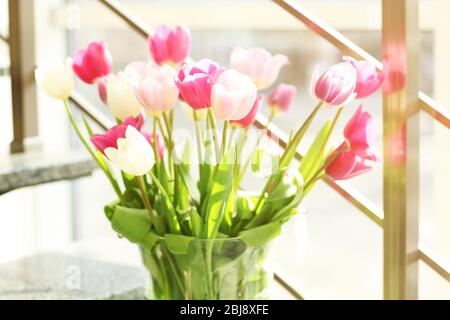Tulipes fraîches dans vase en verre sur les escaliers Banque D'Images