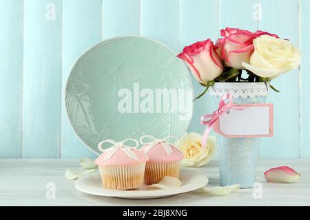 Concept de la fête des mères. Roses dans un vase et cupcakes sur une plaque. Banque D'Images