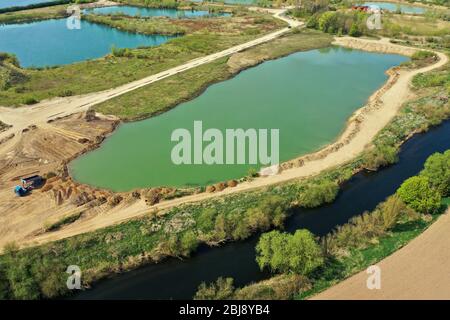 Vue aérienne d'un étang actif de gravier à côté de la rivière Leine près de Sarstedt, Allemagne, avec un camion et des piles de sable Banque D'Images