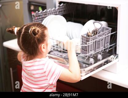 Petite fille jouant avec le lave-vaisselle dans la cuisine Banque D'Images