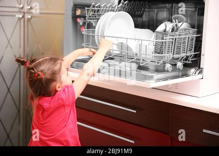 Petite fille jouant avec le lave-vaisselle dans la cuisine Banque D'Images