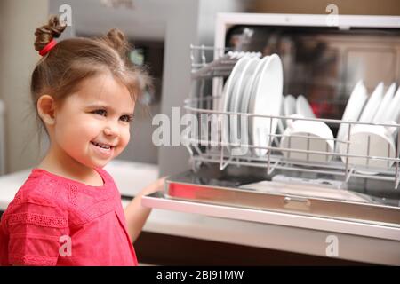 Petite fille et lave-vaisselle dans la cuisine Banque D'Images