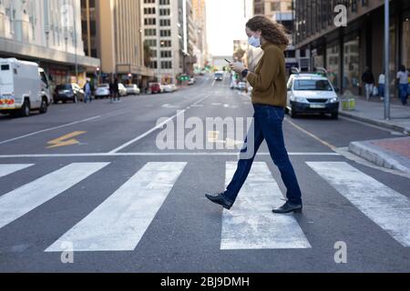 Femme caucasienne portant un masque de protection et marchant dans la rue Banque D'Images