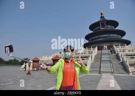 Pékin, Chine. 29 avril 2020. Un touriste pose pour un selfie devant la salle de prière pour de bonnes récoltes au Temple du ciel à Beijing, capitale de la Chine, 29 avril 2020. Le Temple du ciel, site du patrimoine mondial de l'UNESCO temporairement fermé en raison de l'éclosion de la COVID-19, a rouvert ses trois principaux groupes de bâtiments au public mercredi. Les terrains rouverts, à savoir la salle de prière pour la bonne récolte, la voûte impériale du ciel et l'autel de la Mélége circulaire, sont accessibles par un nombre limité de visiteurs par réservation en ligne. Crédit: Peng Ziyang/Xinhua/Alay Live News Banque D'Images