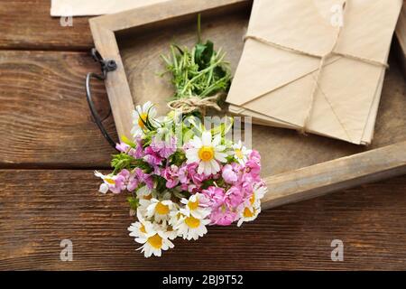 Bouquet de fleurs de prairie avec enveloppes sur table en bois Banque D'Images