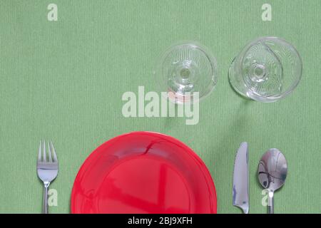 dîner place mettant une plaque rouge avec fourchette argentée et cuillère sur vert Banque D'Images