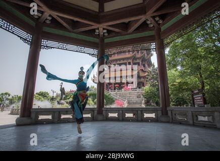 Wuhan, la province chinoise de Hubei. 29 avril 2020. Une danseuse organise une représentation à la Tour de la grue jaune, ou Huanghelou, un monument historique à Wuhan, dans la province de Hubei en Chine centrale, le 29 avril 2020. Comme l'impact de la pandémie COVID-19 s'est estomré, la tour de la grue jaune de Wuhan a été en partie rouverte au public mercredi. Pour l'instant, il y a encore une limite de nombre de visiteurs (300 touristes sont autorisés dans le bâtiment principal toutes les demi-heures) et la réservation en ligne est nécessaire. Crédit: Xiao Yijiu/Xinhua/Alay Live News Banque D'Images