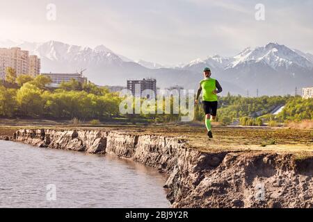 Un homme âgé de près de la rivière avec des bâtiments et l'arrière-plan la montagne le matin. Concept de vie sain Banque D'Images